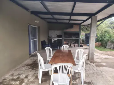 a wooden table and white chairs on a patio at Cabaña papáviejo in Villa de Las Rosas