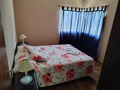 a bedroom with a bed with a flowered blanket and a window at Cabaña papáviejo in Villa de Las Rosas