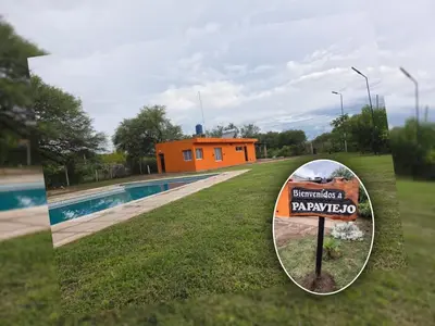 a sign in the grass next to a swimming pool at Cabaña papáviejo in Villa de Las Rosas