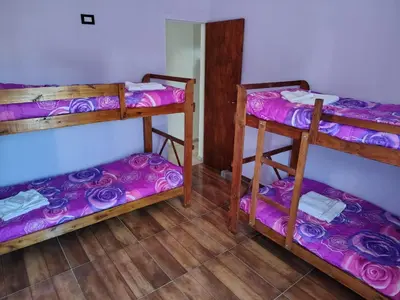 a room with three bunk beds with purple sheets at Cabaña papáviejo in Villa de Las Rosas