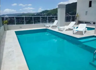 a swimming pool with two white chairs at City Paz in Villa Carlos Paz