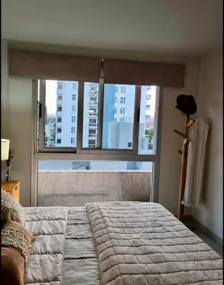 a bedroom with a bed and a large window at City Paz in Villa Carlos Paz