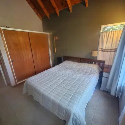 a bedroom with a bed and a wooden cabinet at die lavendel chalet in Villa General Belgrano