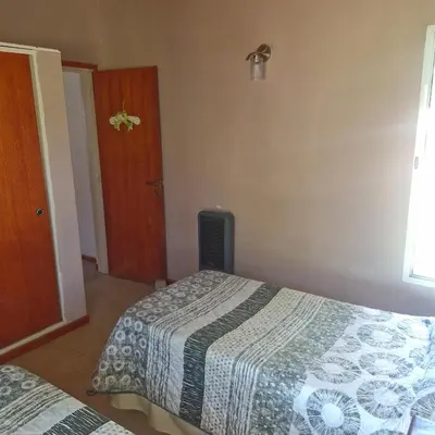 a small bedroom with two beds and a door at die lavendel chalet in Villa General Belgrano