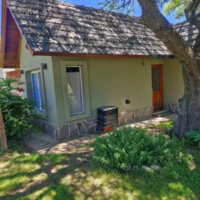 a small yellow house with a tree in the yard at die lavendel chalet in Villa General Belgrano