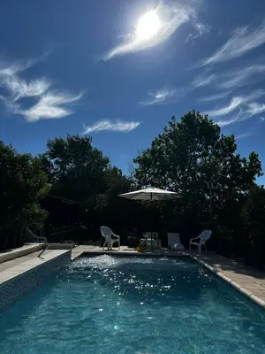 a swimming pool with two chairs and an umbrella at PurinkiWasi - La casa de todos in Los Reartes