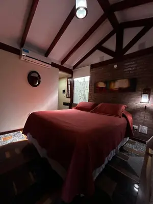 a bedroom with a large bed with red sheets at PurinkiWasi - La casa de todos in Los Reartes