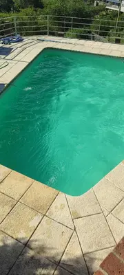 a pool of turquoise blue water in a yard at Casa Villa Carlos Paz in Villa Carlos Paz