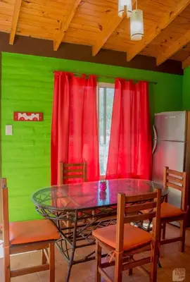 a dining room with a glass table and red curtains at Arcoiris de Cortaderas in Cortaderas