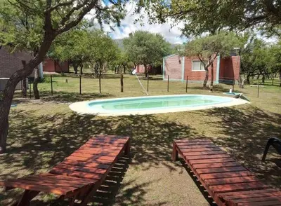 a swimming pool in a yard with two benches at Arcoiris de Cortaderas in Cortaderas