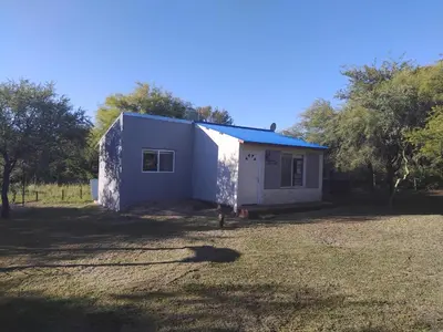 a small white house in a field with trees at Arcoiris de Cortaderas in Cortaderas