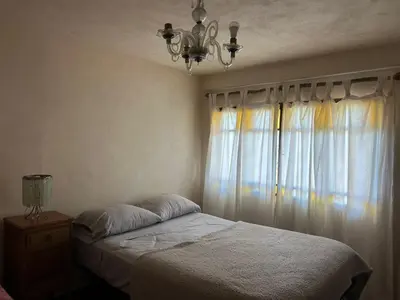 a bedroom with a bed with a chandelier and a window at Casa Puna in Alta Gracia