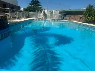 a large blue swimming pool with a palm tree silhouette at Complejo Alfa Iii in Villa Carlos Paz