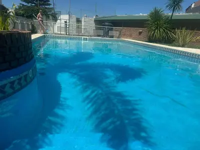 a large blue swimming pool with a woman standing next to it at Complejo Alfa Iii in Villa Carlos Paz