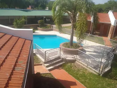 a swimming pool with a palm tree next to a building at Complejo Alfa Iii in Villa Carlos Paz
