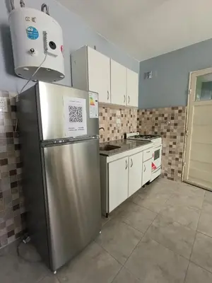 a kitchen with a stainless steel refrigerator and white cabinets at Depto Zenon para 3 personas in Pilar