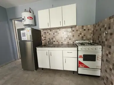 a kitchen with white cabinets and a stove and refrigerator at Depto Zenon para 3 personas in Pilar
