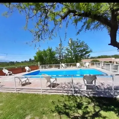 a swimming pool with chairs and a fence around it at Cabañas Nuestro Valle Cura Brochero in Villa Cura Brochero