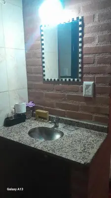 a bathroom sink with a mirror on a brick wall at Cabañas Nuestro Valle Cura Brochero in Villa Cura Brochero