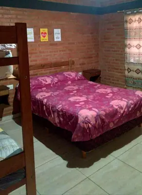 a bedroom with a bed with a pink comforter at Cabañas Nuestro Valle Cura Brochero in Villa Cura Brochero