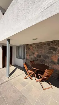 a patio with two chairs and a table and a stone wall at Complejo Carde Housing in Villa Carlos Paz