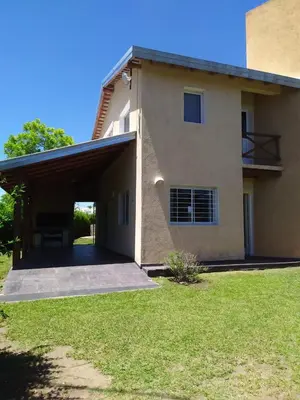 a house with a garage and a grass yard at Las Tole - Potrero de Garay in La Estancia