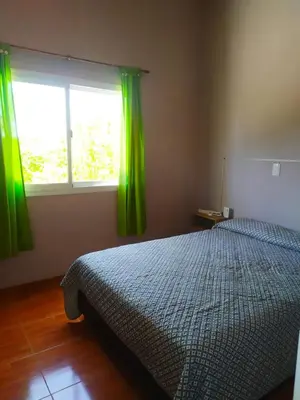 a bedroom with a bed and a window with green curtains at Las Tole - Potrero de Garay in La Estancia
