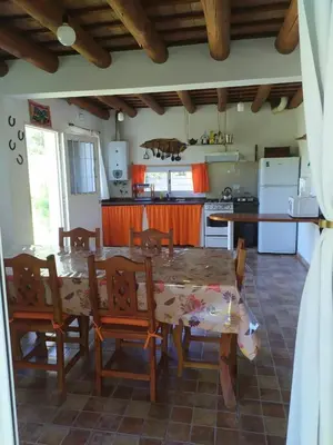 a dining room with a table and chairs and a kitchen at Las Tole - Potrero de Garay in La Estancia