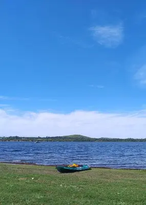 a kayak laying on the grass next to a body of water at cabaña el lago in San Ignacio