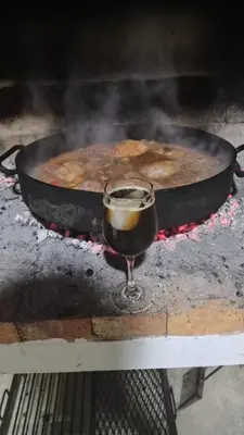 a glass of wine next to a pan of food at cabaña el lago in San Ignacio
