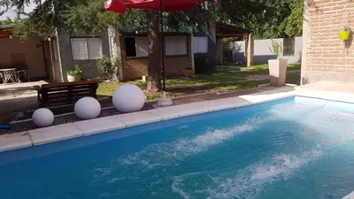 a swimming pool with white balls and an umbrella at Cabañas El DESCANSO in Cordoba