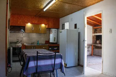 a kitchen with a table with chairs and a refrigerator at Cabañas El DESCANSO in Cordoba