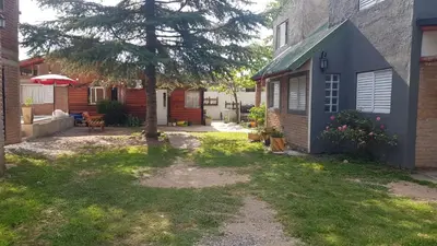 a yard with a tree and a house at Cabañas El DESCANSO in Cordoba