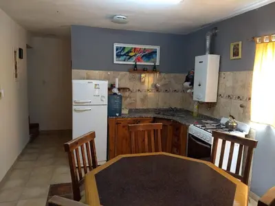 a kitchen with a table and a white refrigerator at Cabañas El DESCANSO in Cordoba