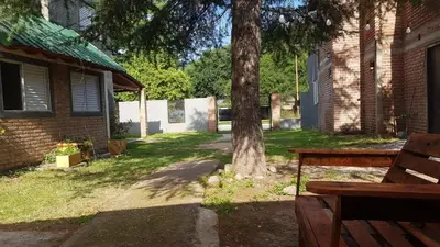 a bench sitting next to a tree in a yard at Cabañas El DESCANSO in Cordoba