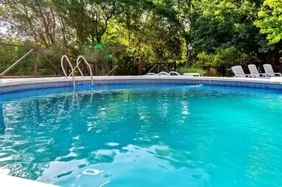 a swimming pool with chairs and a fountain at Cabañas Lorelei in Villa General Belgrano