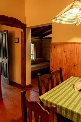 a dining room with a table and chairs and a bench at Cabañas Lorelei in Villa General Belgrano