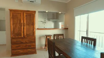 a dining room with a wooden table and a kitchen at Vila Aparts in Mina Clavero