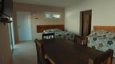 a dining room with a table and a bed and a couch at Vila Aparts in Mina Clavero
