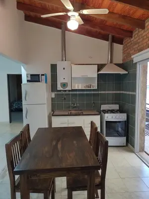 a kitchen with a wooden table and a refrigerator at Vila Aparts in Mina Clavero