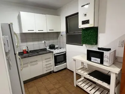 a small kitchen with white cabinets and a white refrigerator at Estrada 59 Nueva Cordoba in Cordoba