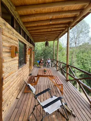 a porch of a log cabin with two chairs on it at La retama in Alta Gracia