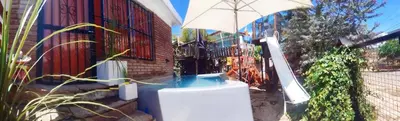 a pool with an umbrella next to a house at Casa centrica in Villa Carlos Paz