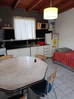 a kitchen with a table and chairs and a bed at Alojamiento Nory's in Villa Carlos Paz