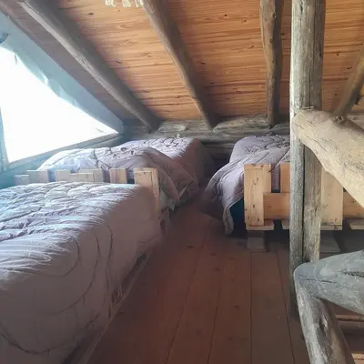 a room with three beds in a log cabin at Cabaña Eluney in Villa Ciudad Parque