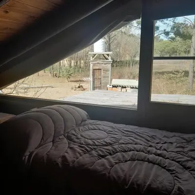 a bed in a room with a window at Cabaña Eluney in Villa Ciudad Parque