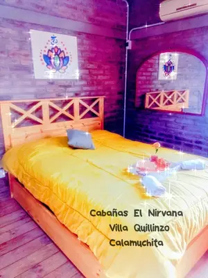 a bedroom with a large yellow bed with a table at Cabañas El Nirvana Villa Quillinzo in Villa Quillinzo