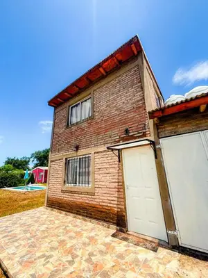a brick house with two white garage doors at Cabañas El Nirvana Villa Quillinzo in Villa Quillinzo
