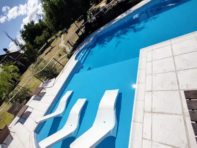 a swimming pool with white plastic chairs in it at Rincón Soñado in Las Rabonas