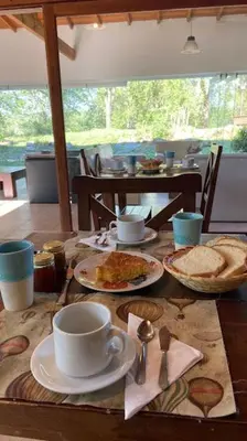 a table with plates of food and a cup of coffee at Posada La Rosita - Casa in Santa Rosa de Calamuchita